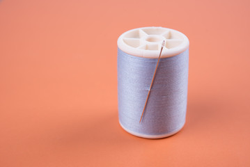 closeup needles, thread spool on wooden background.