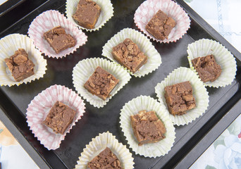 Close up image of chocolate brownies in cases on a baking tray.