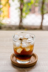 Glass of cola with ice on wooden background