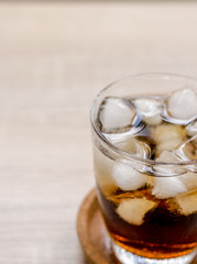 Glass of cola with ice on wooden background