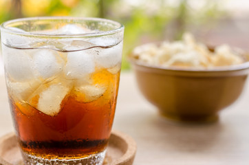 close up in dried squid and cola in glass on wooden background