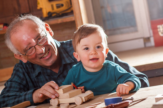 Senior carpenter and his grandson having fun in the workshop