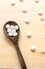 Fototapeta na wymiar medicine tablets and wooden spoon on wood background