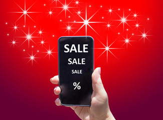 The phone with text SALE in female hand on the red background