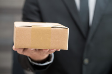 Businessman in suit giving brown box