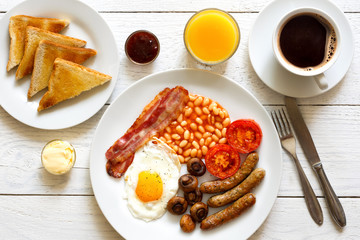 Traditional fried English breakfast with orange juice and coffee from above.