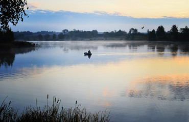 A fisherman in a boat sailing in the morning mist