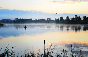 A fisherman in a boat sailing in the morning mist