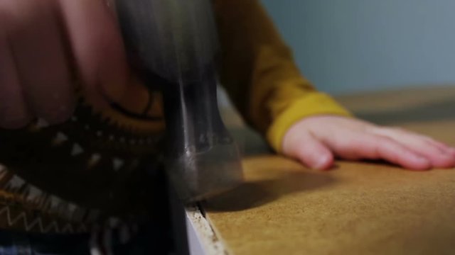 Closeup Shot Of Little Boy Using A Hammer To Nail A Flat Pack Wardrobe