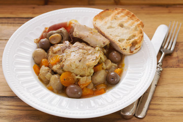 rabbit stew with mushrooms and carrot on white dish on brown wooden background