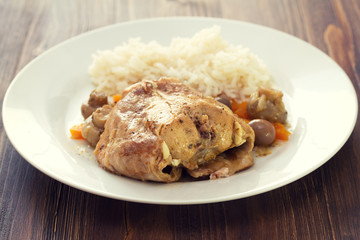 rabbit stew with mushrooms and carrot and boiled rice on white dish on brown background