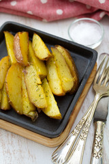 fried potato on black frying pan on white wooden background