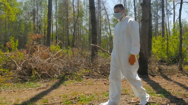 A guy in a special suit removes trash in forest