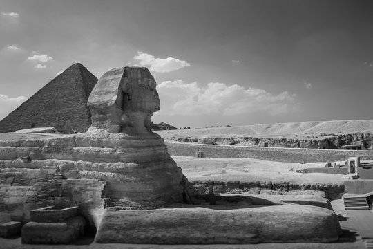 The full profile of the Great Sphinx with the pyramid in the background in Giza. Egypt. Black and white photo.