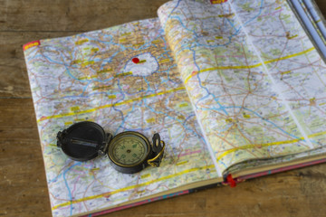 One compass on a roads guide book on a wooden background