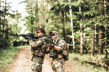 Fototapeta premium military. Two Armed man in a zone of armed conflict soldier in uniform targeting with assault rifle outdoors. two solders with weapon