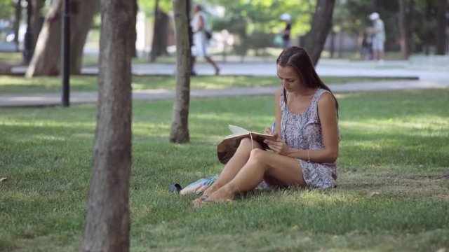 Young woman writes in her diary in the park