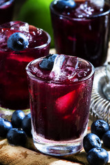 Maroon alcoholic cocktail with berries blueberries and ice, sele