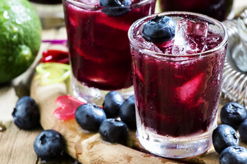 Maroon alcoholic cocktail with berries blueberries and ice, sele