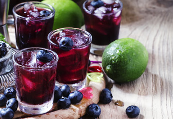 Maroon alcoholic cocktail with berries blueberries and ice, sele
