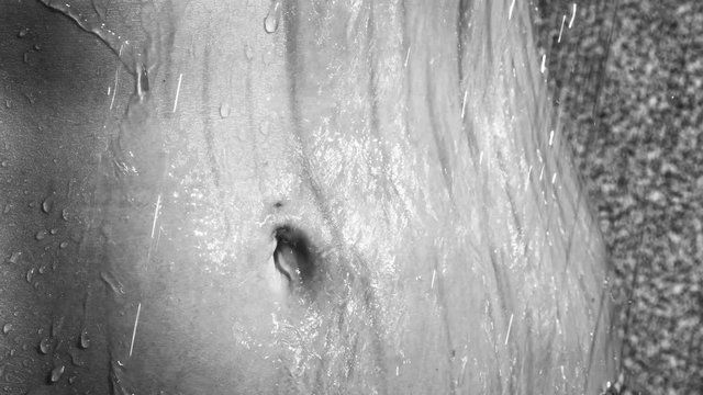 Closeup of woman stomach under outdoor shower - black and white video