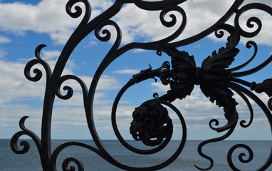 Fototapeta na wymiar Ocean and sky view through wrought iron gate on the Cliff Walk in Newport, RI