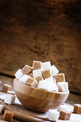 Cubes of white and brown sugar, wooden bowl, selective focus
