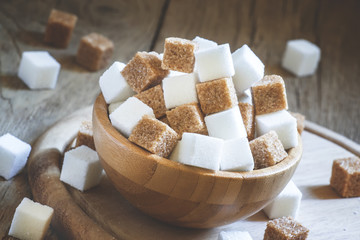 Cubes of white and brown sugar, wooden bowl, selective focus