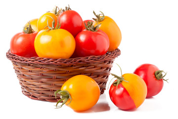 red and yellow tomatoes in a wicker basket isolated on white background