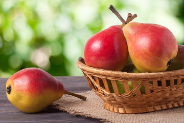 pears in a wicker basket on  wooden table with  blurred green background