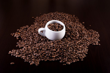 Cup full of coffee beans on a dark wooden background