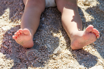 Little girl sitting on the sand and playing with plastic toys.