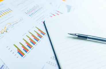 close up of pen on notepad with business documents in background. Business concept. Photo with selective focus and blue light filter.