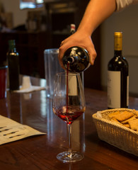 Mann füllt Wein von einer Flasche in ein Glas bei einer Weinverkostung in Italien