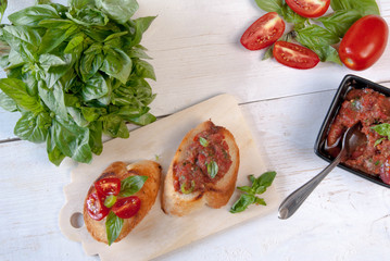 Snack in the Italian style: bruschetta with tomato and basil. At the rustic wooden table. 