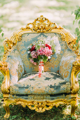 Close-up, bouquet of flowers roses with red ribbons and withe lace stand on vintage chair outdoors...