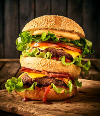 Homemade tasty double burger with beеf, salad, bacon, tomatoes