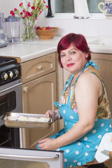 Mature woman baking muffins at home