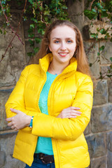 Obraz premium Outdoor portrait of a young woman wearing bright yellow jacket, vertical image