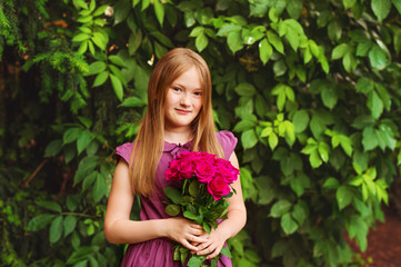 Portrait of adorable little girl of 8-9 years old, holding beautiful bouquet of bright pink roses