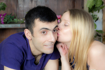 Woman kissing man on the cheek. Young couple in the village house.