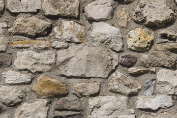 Old grey and brown rough stone wall, closeup texture background, selective focus, shallow DOF