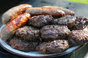 Hamburger and brats grilled and ready to eat - obrazy, fototapety, plakaty