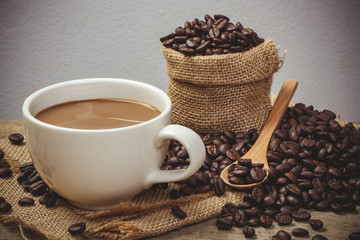 Hot Coffee cup with Coffee beans on the wooden table and the bla