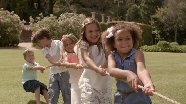 Five children pulling rope having tug of war in park