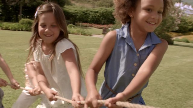 Five children pulling rope having tug of war in park
