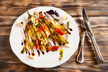 Fried vegetable marrow and tomatoes on white plate