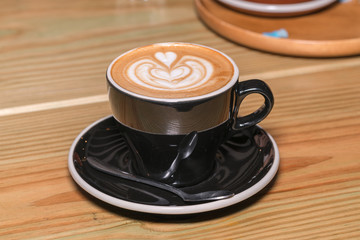 Cup of hot latte art coffee on wooden table

