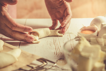 Baker making croissants on rustic wood background