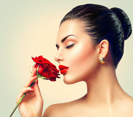 Fashion brunette model girl face portrait with red rose in her hand